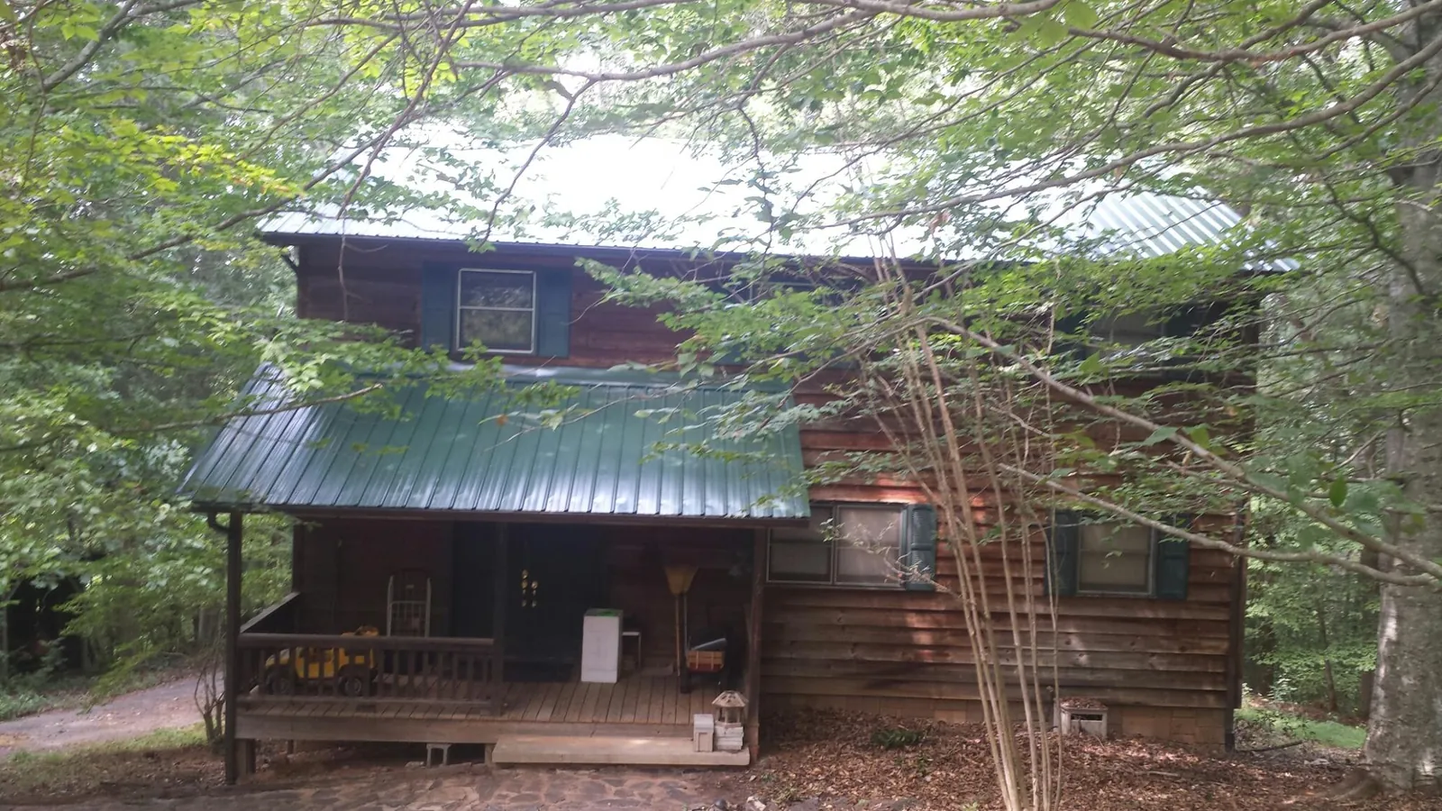 Green metal roof and covered porch on a log cabin in Morton Grove