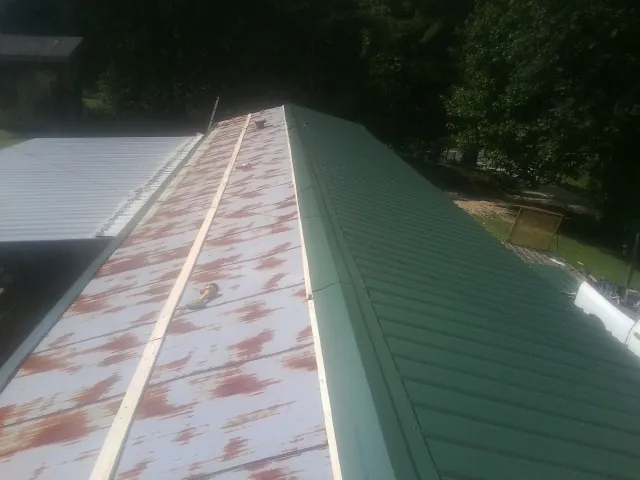 Old rusted panels beside newly installed green metal roofing — Wind Damage Roof Repair by Roofing Brothers in Morton Grove