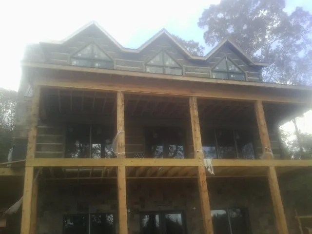 Dormers and porch framing on a large log home under construction — Roof Coating work by our crew in Morton Grove