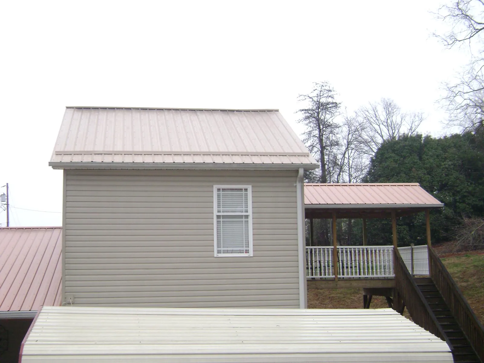 Tan metal roofs on a two story addition and attached porch, from a Roof Replacement job in Morton Grove