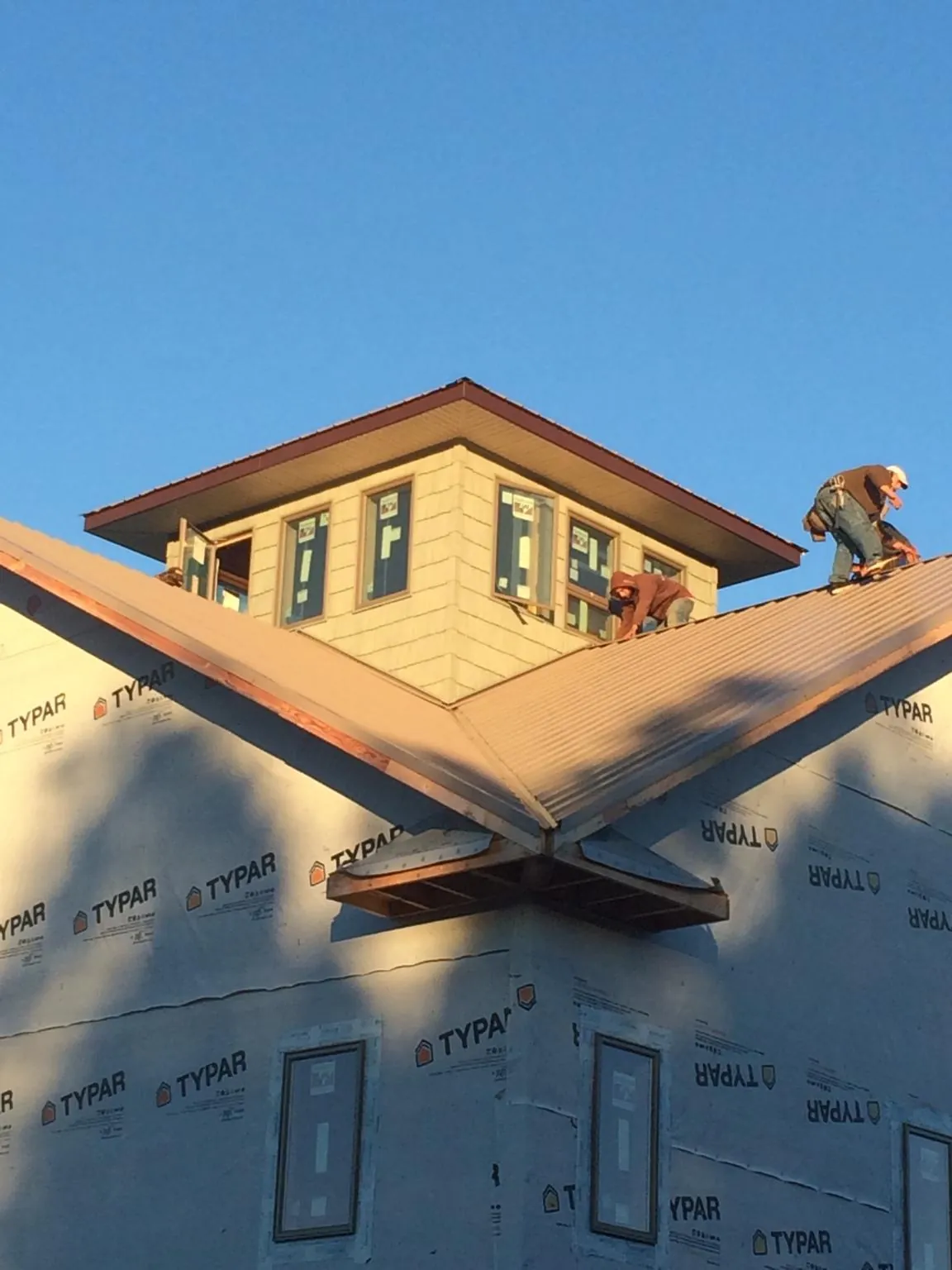 Roofers working around a rooftop cupola on a new metal roof at sunset — Roof Waterproofing in Morton Grove by Roofing Brothers